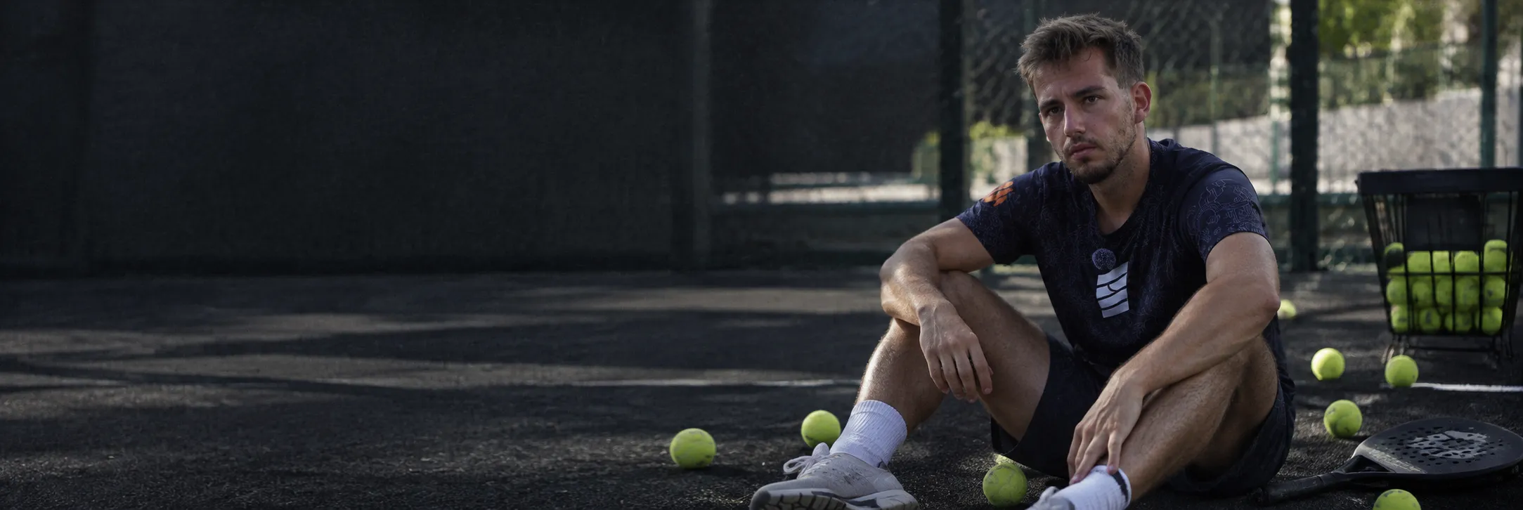 Dani Hoyo sitting on a padel court, surrounded by balls