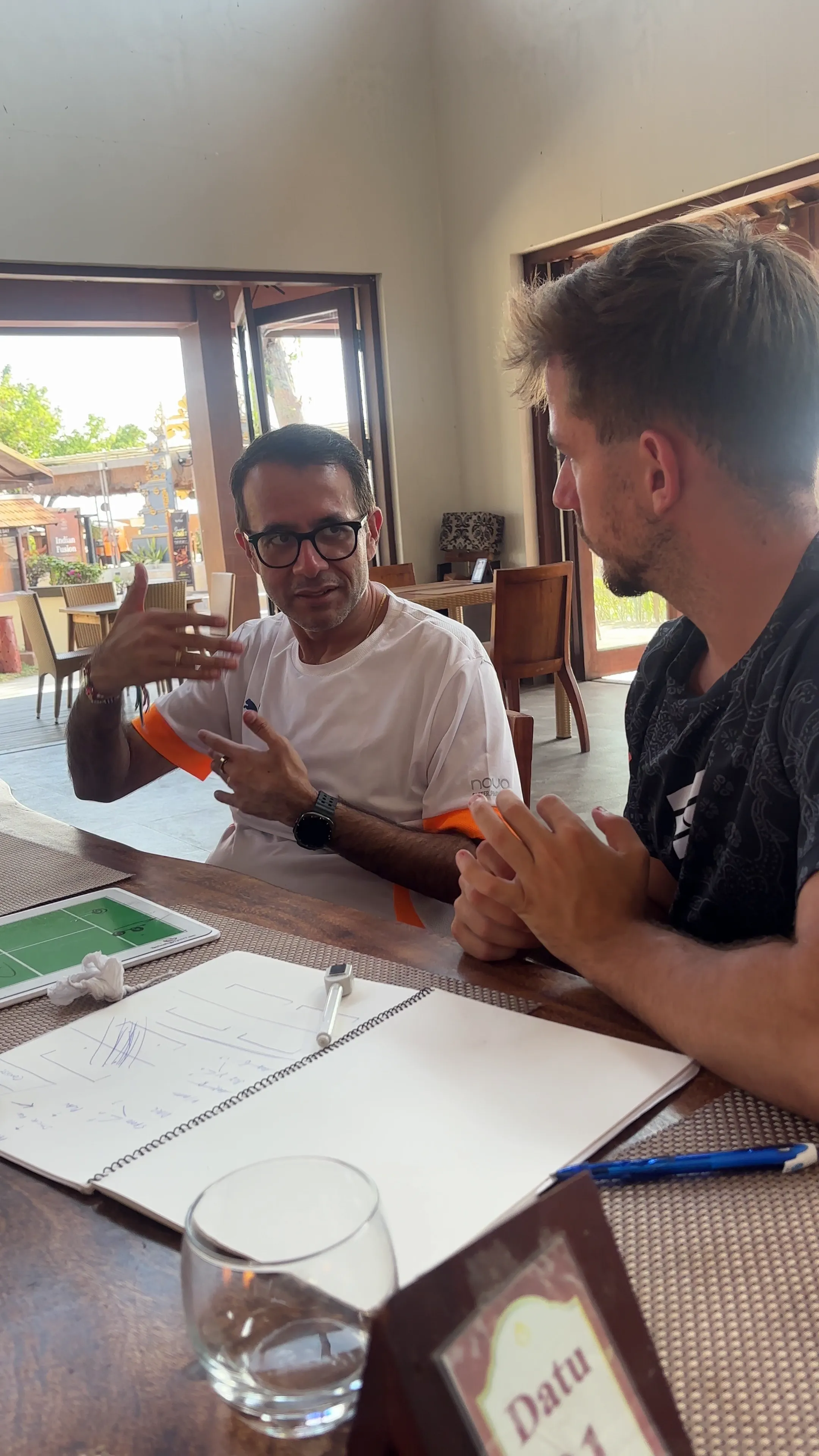 Anoop talking with Dani at a table, with notes